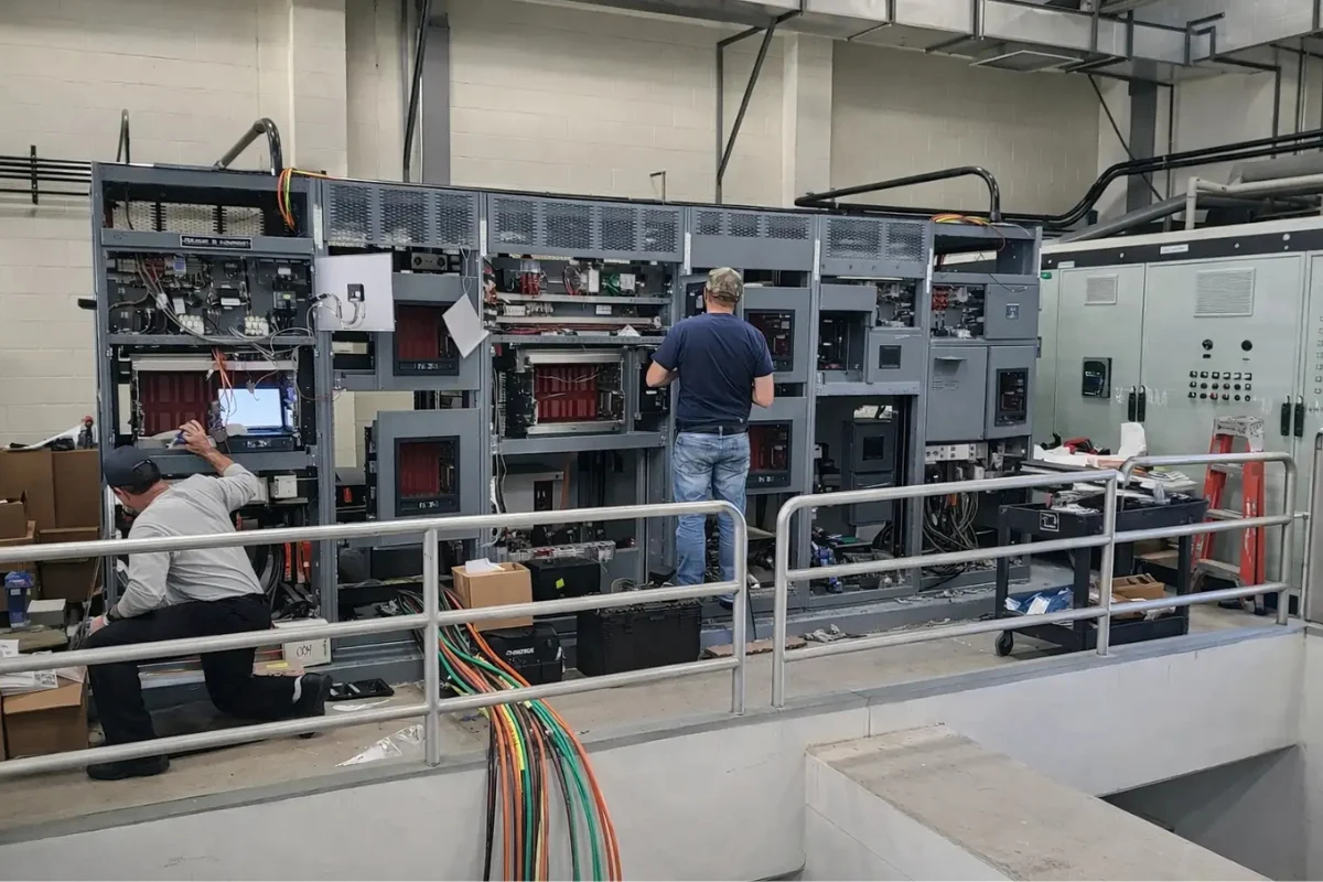Commercial electricians installing and wiring large electrical panels for infrastructure power systems in Baltimore, MD.